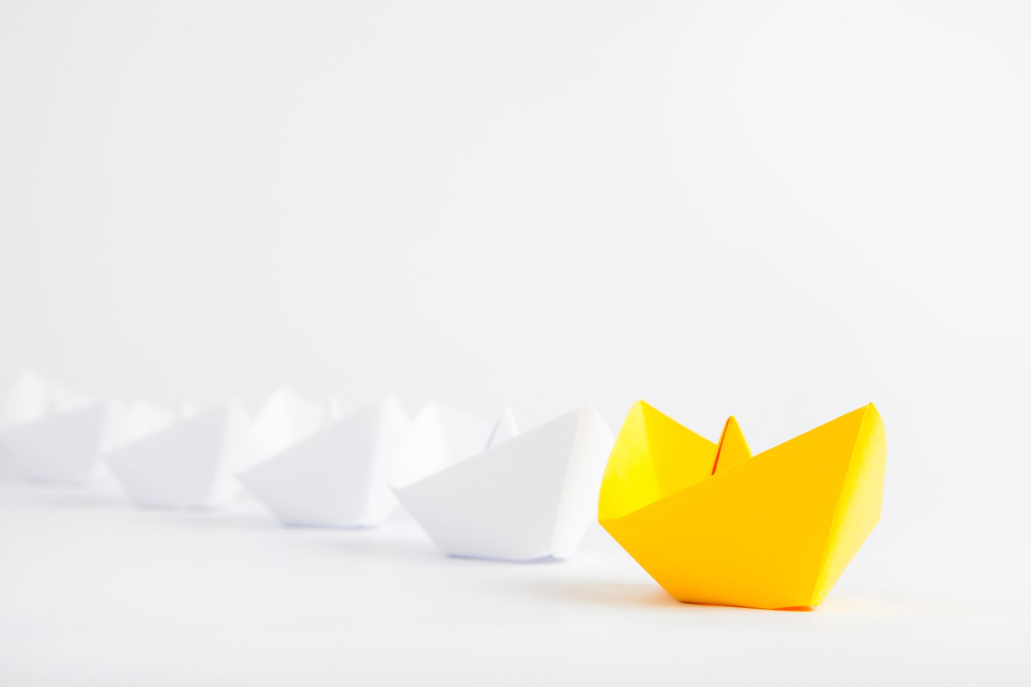 Yellow-paper-ship-leading-among-white-ships